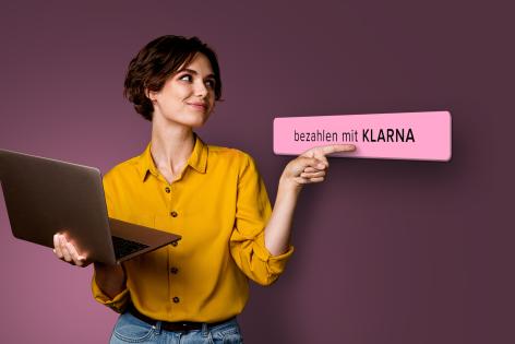Frau mit Notebook, die sich über die neue Klarna Erweiterung freut.