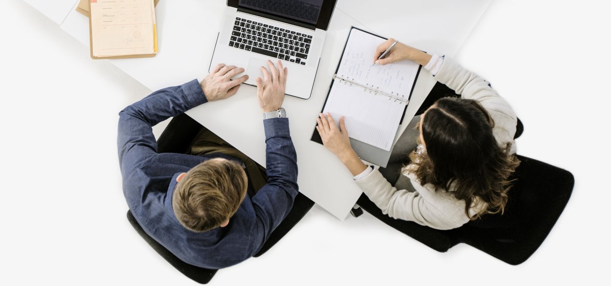 Frau und Mann an einem Arbeitsplatz erstellen eine Rechnung.