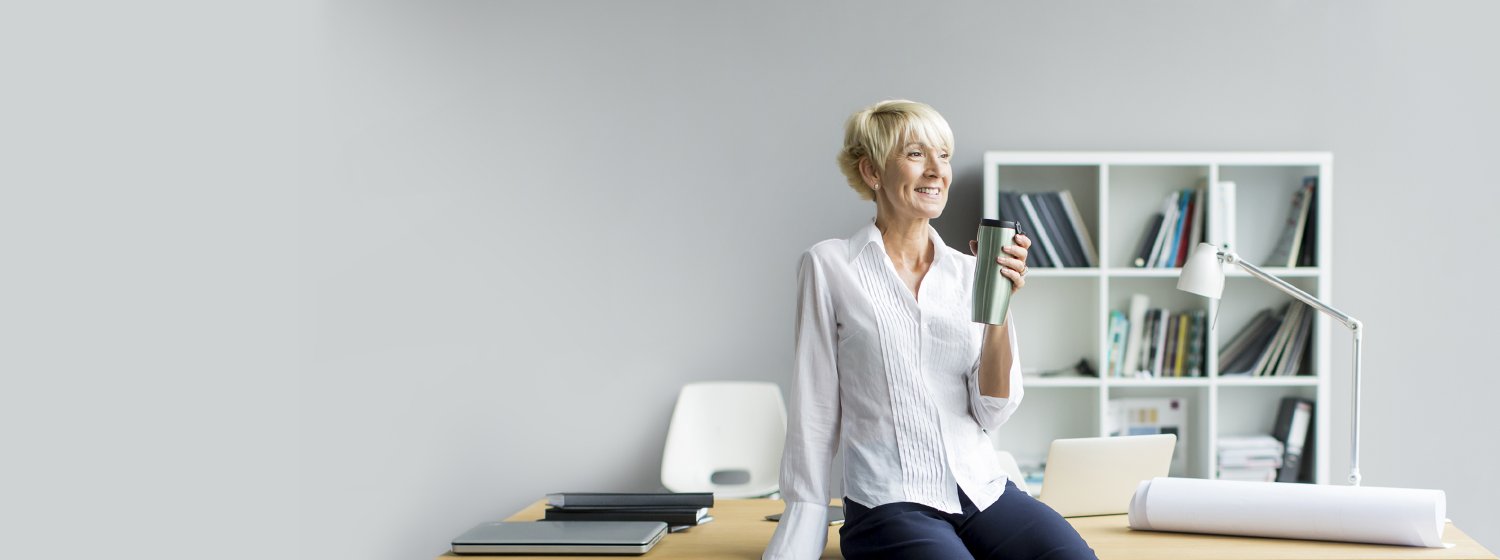Frau sitzt entspannt auf ihrem Schreibtisch wärend SIQUANDO Spezialisten ihre individuellen Wünsche umsetzen.