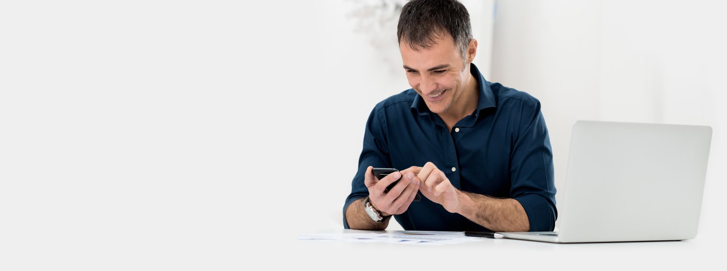 Mann vor Notebook ruft mit seinem Telefon die Spezialisten Hotline für eine kurze Frage an.