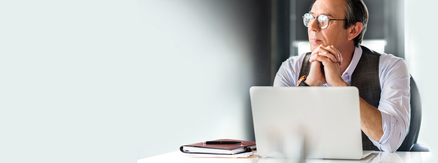 Mann, der nachdenklich vor seinem Notebook sitzt.