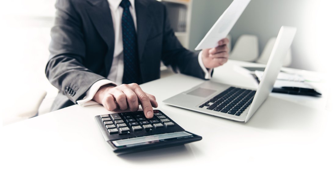 Mann, der Umsatzsteuer mit einem Taschenrechner ausrechnet, da er keine Erweiterung Umsatzsteueranpassung hat.
