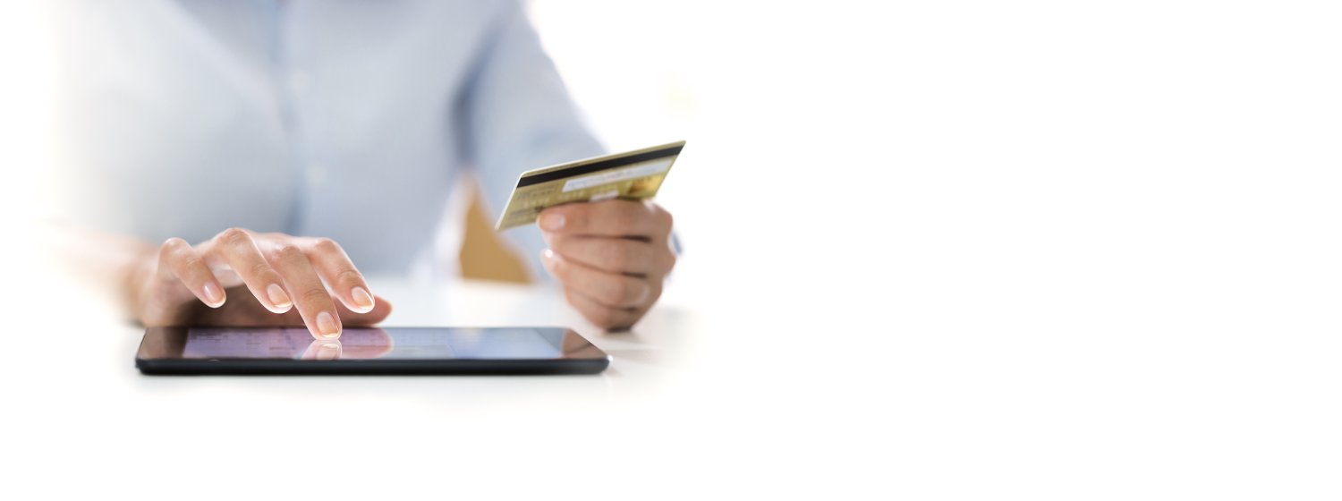 Person, die eine Kreditkartennummer auf ein Tablet abtippt.