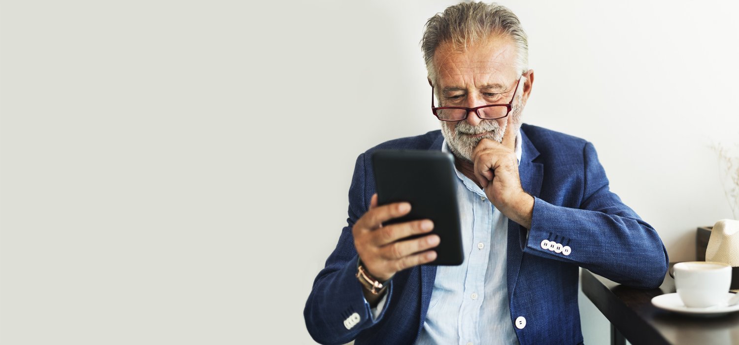 Mann mit Bart schaut auf sein Handy und freut sich über die Erweiterung digitale Güter.