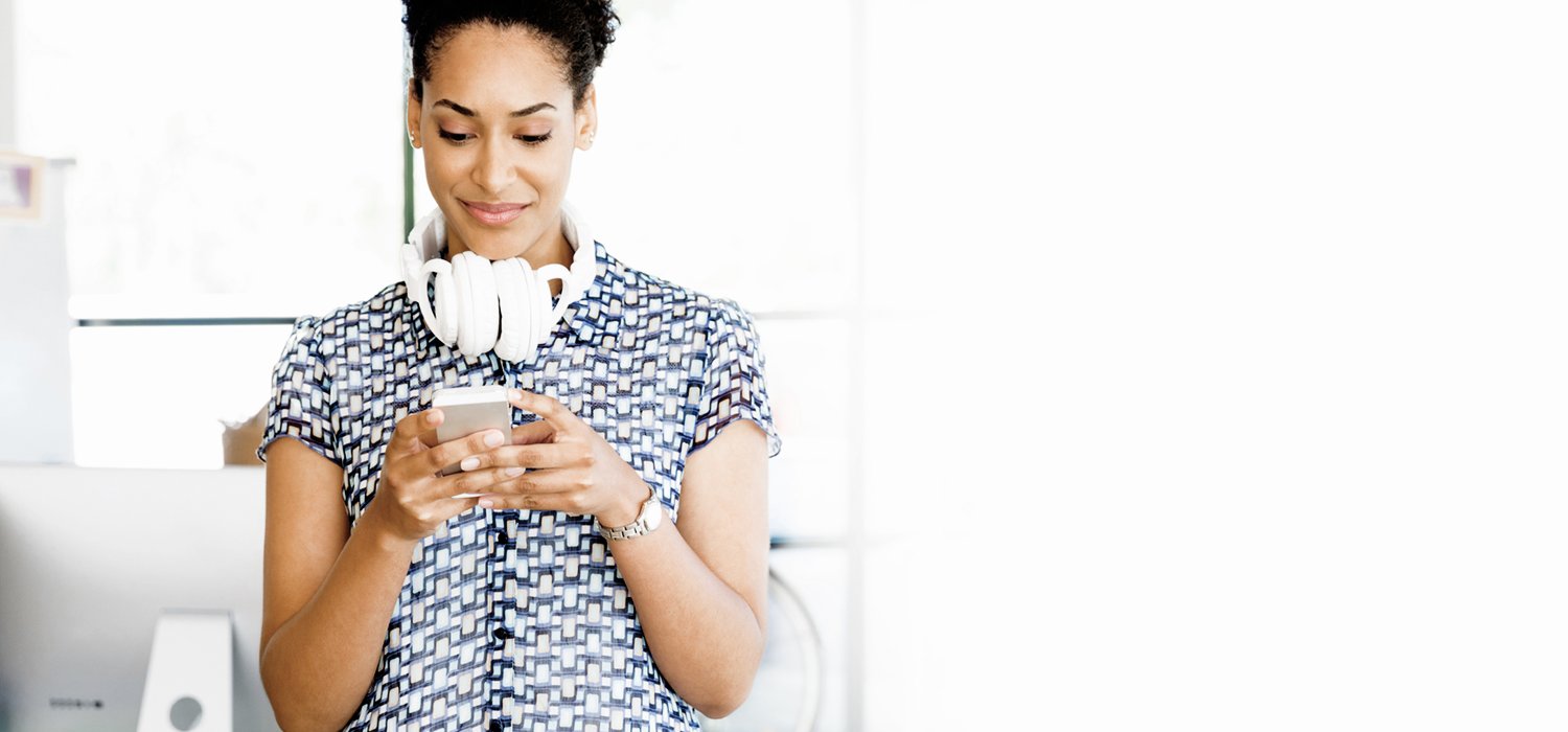 Frau mit Kopfhörern schaut auf Ihr Handy und freut sich über die Erweiterung digitale Güter.